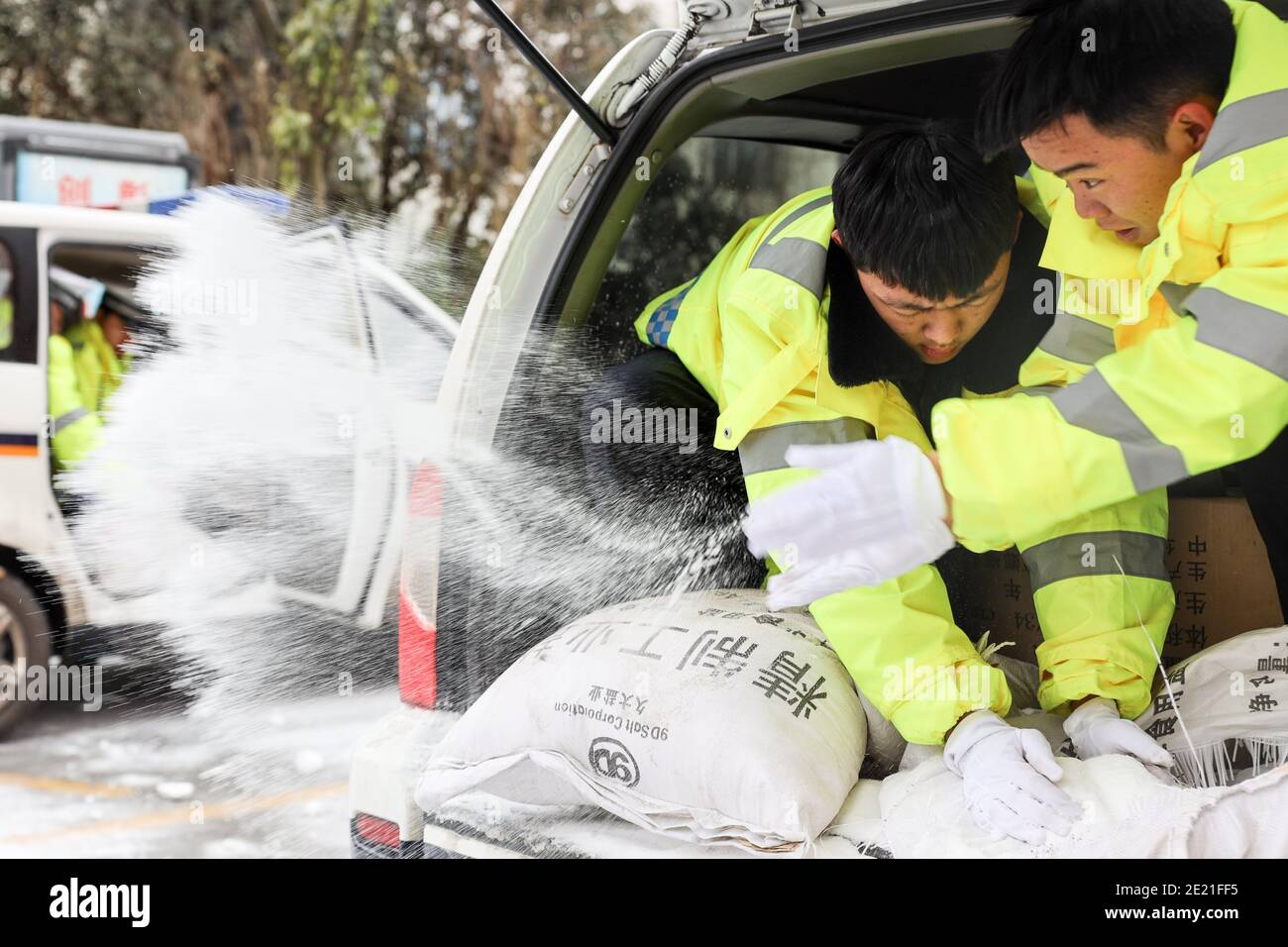(210111) -- PANZHOU, 11. Januar 2021 (Xinhua) -- Verkehrspolizisten verbreiten industrielles Salz, ein Eisschmelzmittel, auf der Elangpu-Brücke in der Stadt Panzhou im Südwesten Chinas, Provinz Guizhou, 11. Januar 2021. Die jüngste starke Kältewelle hat in Panzhou und vielen anderen Orten in Guizhou zu einer Staubildung geführt. Rund 400 Verkehrspolizisten in Panzhou arbeiten nun rund um die Uhr daran, die Straßenflächen der Eisverkleidungen in der Stadt zu entfernen. Das fluoreszierende Grün auf ihren Jacken scheint die wärmste Farbe in einem frostigen Winter zu sein. (Xinhua/Ou Dongqu) Stockfoto