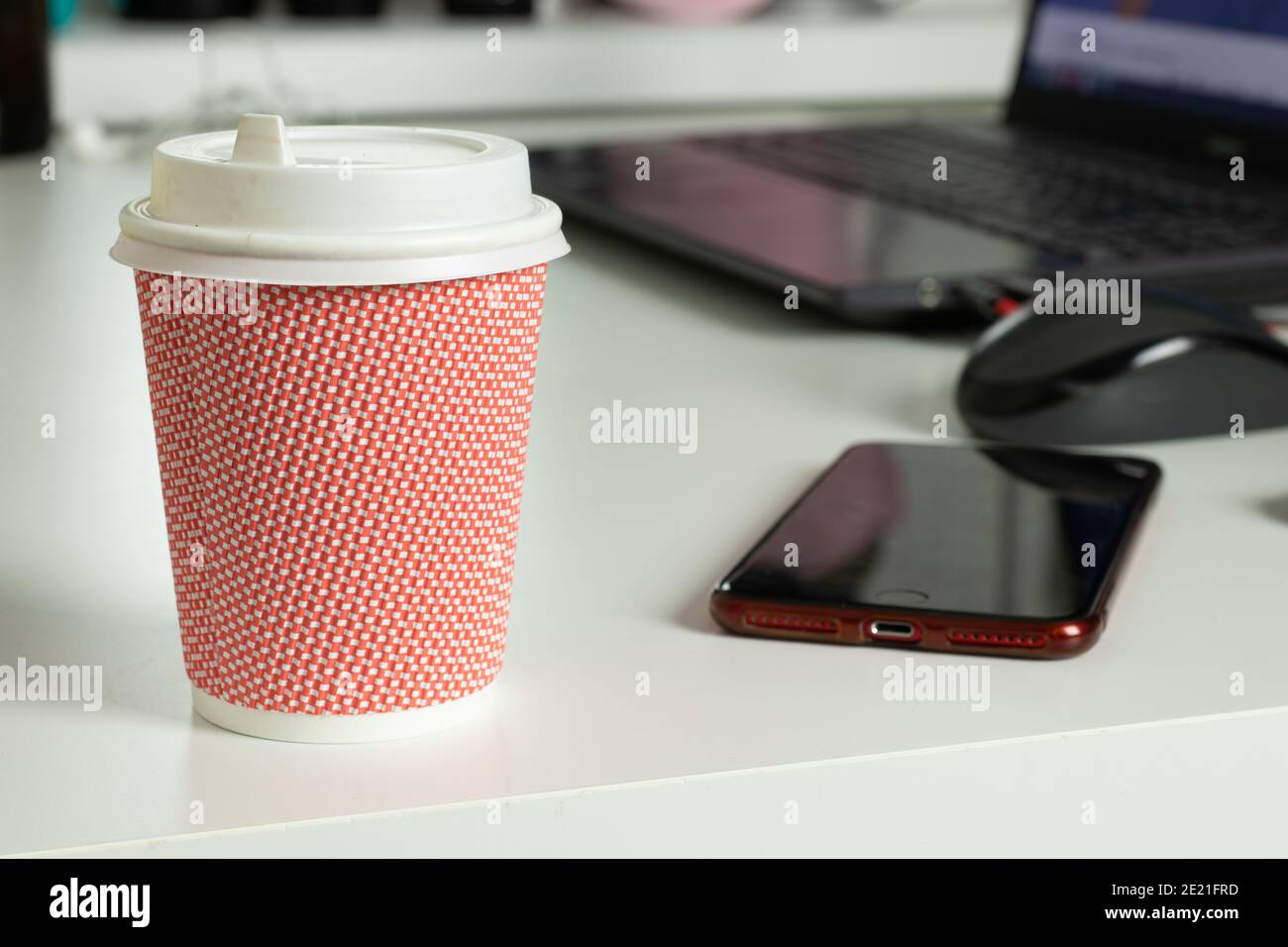 Büroarbeitsplatz Schreibtisch mit Coffee to go Tasse, Telefon und Laptop auf verschwommenem Hintergrund Stockfoto