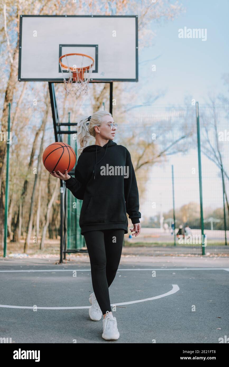 Volle Länge der glücklichen Dame zu Fuß auf Basketballplatz während Wegschauen Stockfoto