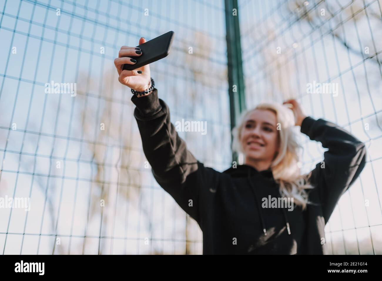 Portrait der glücklichen schönen Dame mit Handy während der Herstellung Foto auf Basketballplatz Stockfoto