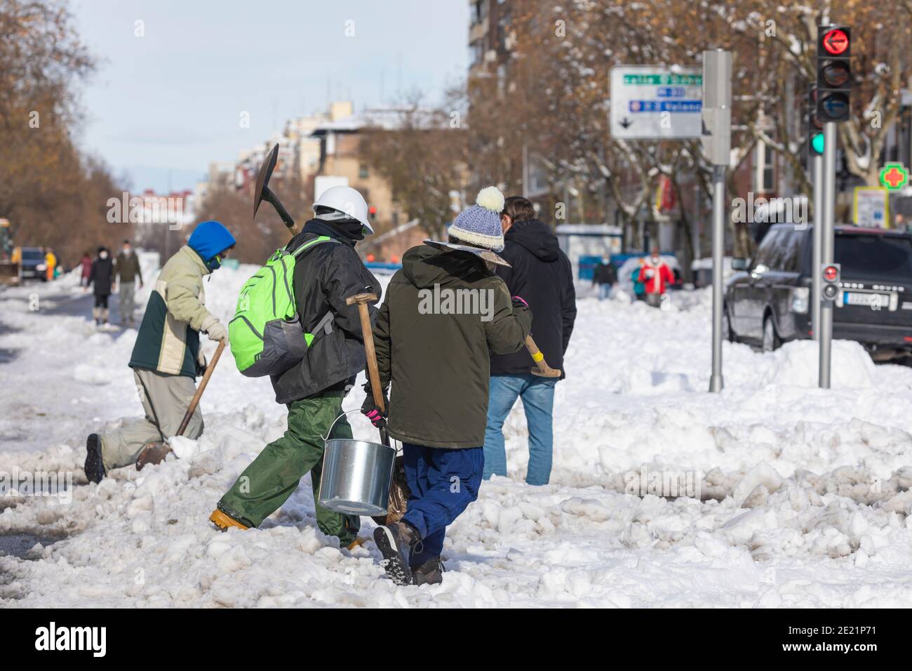 Madrid, Spanien - 10. Januar 2021: Bürger und Nachbarn von Madrid, die an einem verschneiten Tag zusammenarbeiten und den Schnee von den Straßen und Autobahnen säubern, Stockfoto