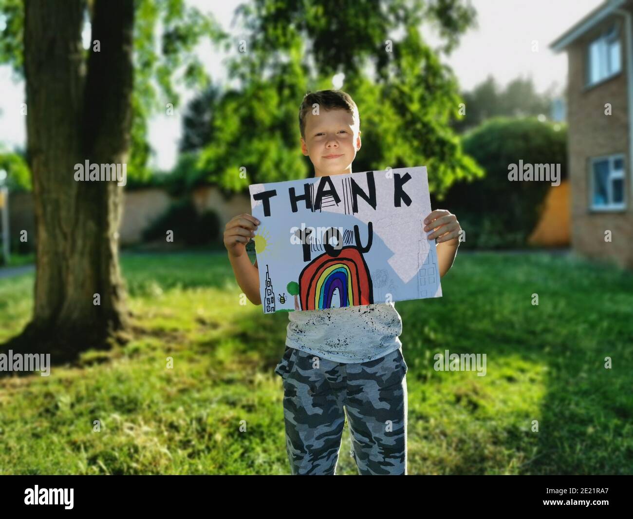 Ein kleiner Junge hält eine Regenbogenzeichnung und das Danke Ihre Nachricht an das medizinische Personal, das durch den Covid-19 arbeitet Pandemie Stockfoto