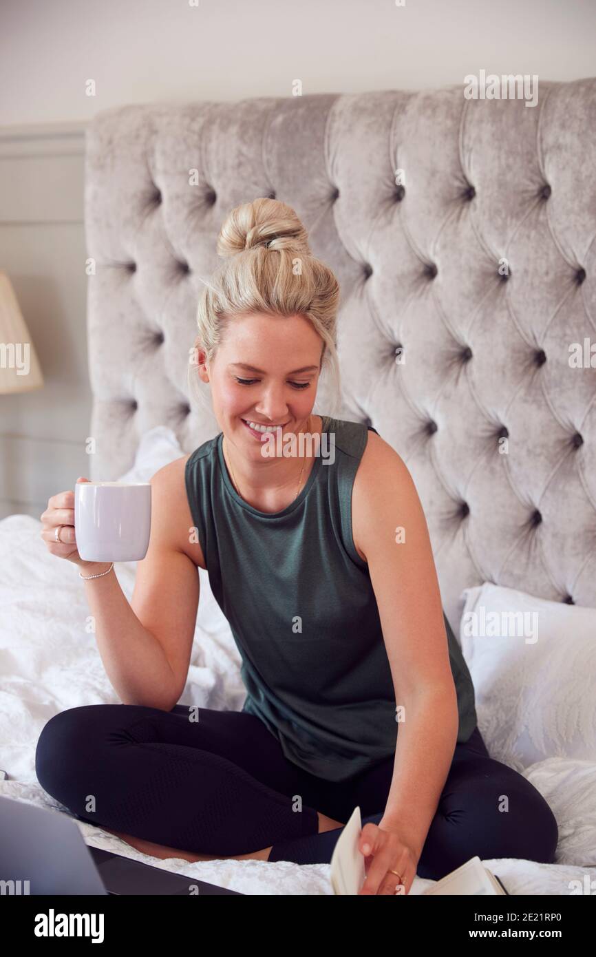 Geschäftsfrau Sitzt Auf Dem Bett Mit Laptop Und Tagebuch Arbeiten Aus Zu Hause Stockfoto
