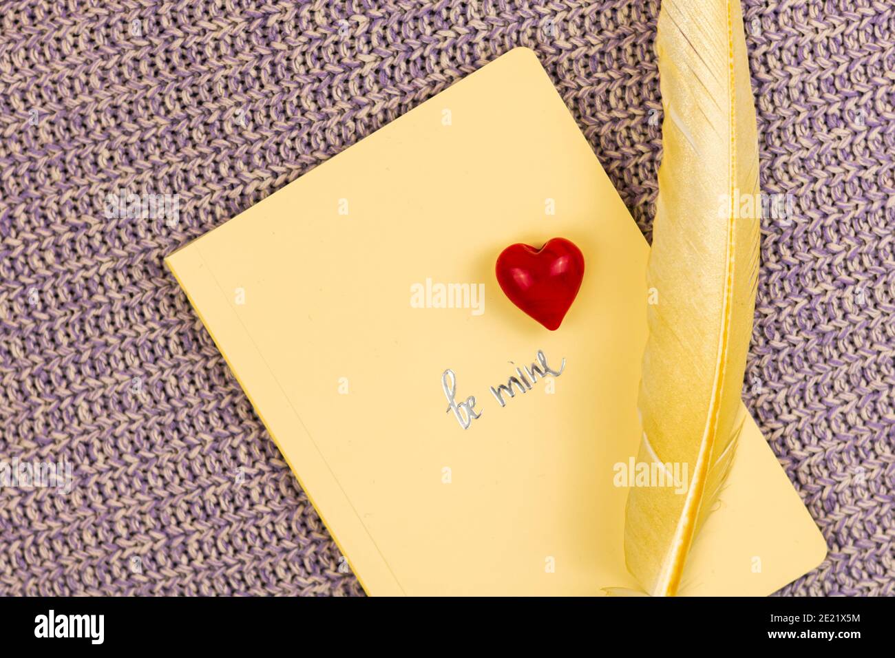 Valentinstag Grußkarte Hintergrund auf Strickpullover und Text Be meins, Komposition mit rotem Herz, Notizbuch und farbiger Feder. Hochwertige p Stockfoto