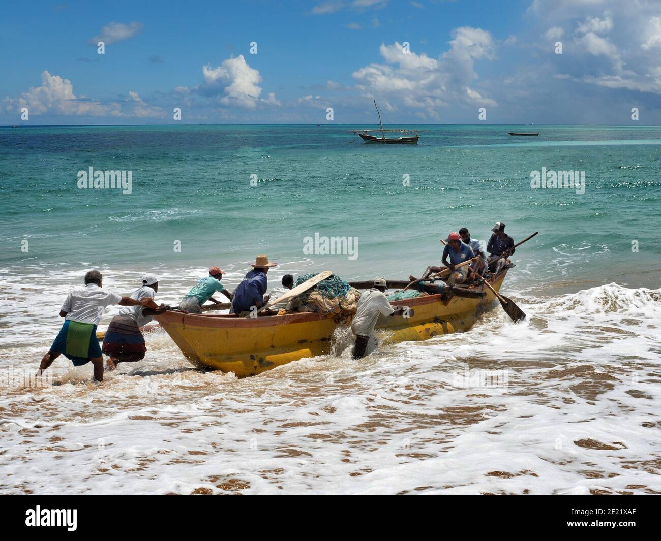 TANGALA, SRI LANKA - 15. März 2019: Asiatische Fischer schieben Holzboot auf dem Meer. Stockfoto