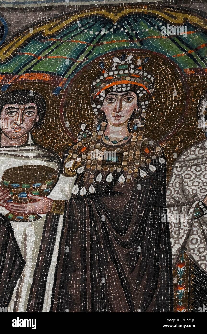 Theodora, Kaiserin des byzantinischen oder östlichen Römischen Reiches, hält einen Kommunion-Kelch, während sie mit Mitgliedern ihres Gefolges steht. Byzantinisches Mosaik in der Basilika di San Vitale in Ravenna, Emilia-Romagna, Italien. Das Mosaik wurde in den 500s v. Chr. erschaffen, ein paar Jahre nachdem Ravenna vom byzantinischen Reich aus den Ostrogoten gefangen wurde. Stockfoto