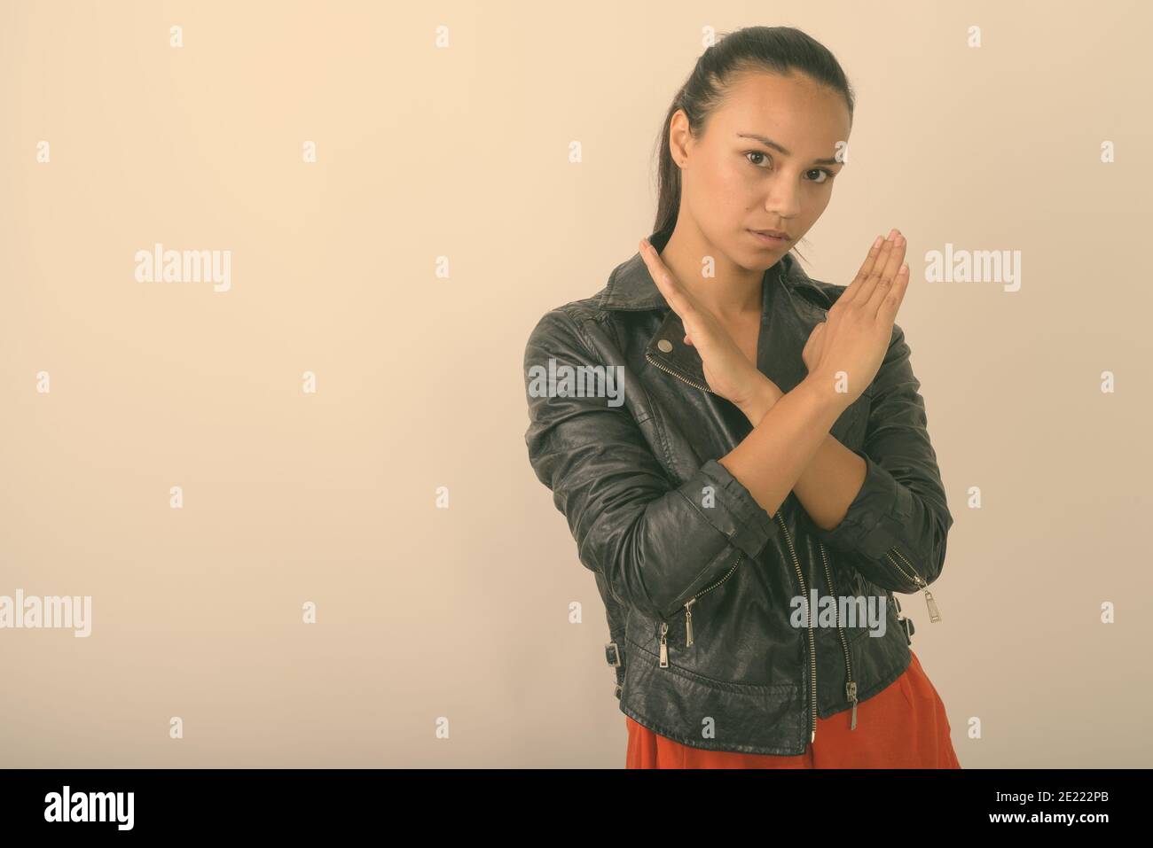 Studioaufnahme einer jungen asiatischen Frau mit Stop-Hand-Geste Mit beiden Händen, während das Tragen Lederjacke auf weißem Hintergrund Stockfoto