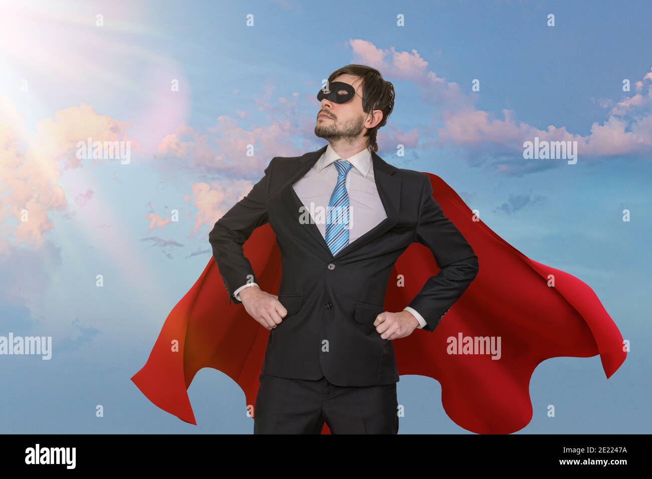 Lustige tapfere Geschäftsmann in Anzug als Superheld. Himmel im Hintergrund. Stockfoto