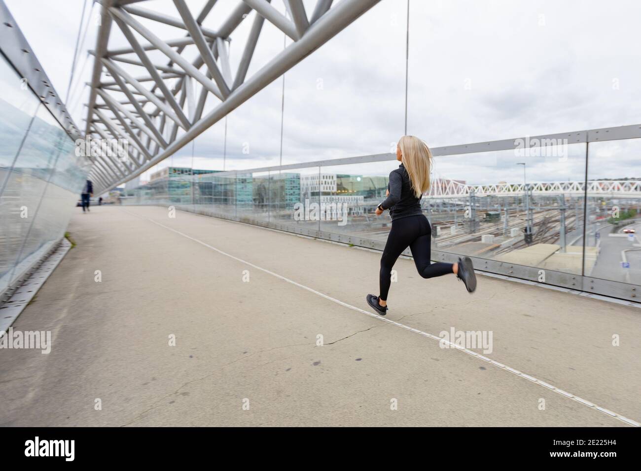 Läuferin in schwarzem Workout-Outfit im modernen City-Umfeld Stockfoto