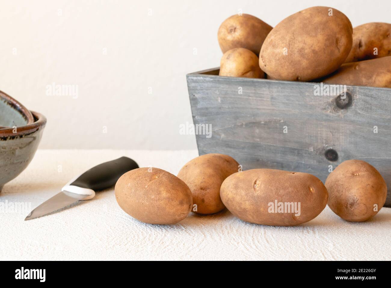 Kartoffeln und Küchenmesser aus nächster Nähe auf dem Küchentisch Stockfoto
