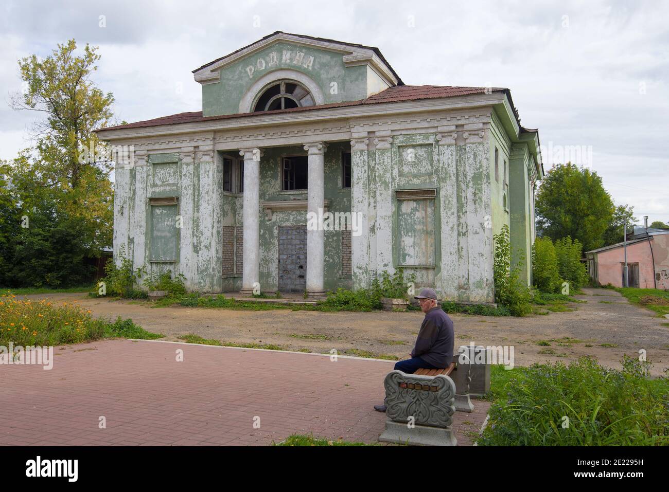 KOTELNICH, Russland - 15. SEPTEMBER 2018: Alter Mann sitzt auf einer Bank in der Nähe der geschlossenen Kino 'Rodina' Stockfoto