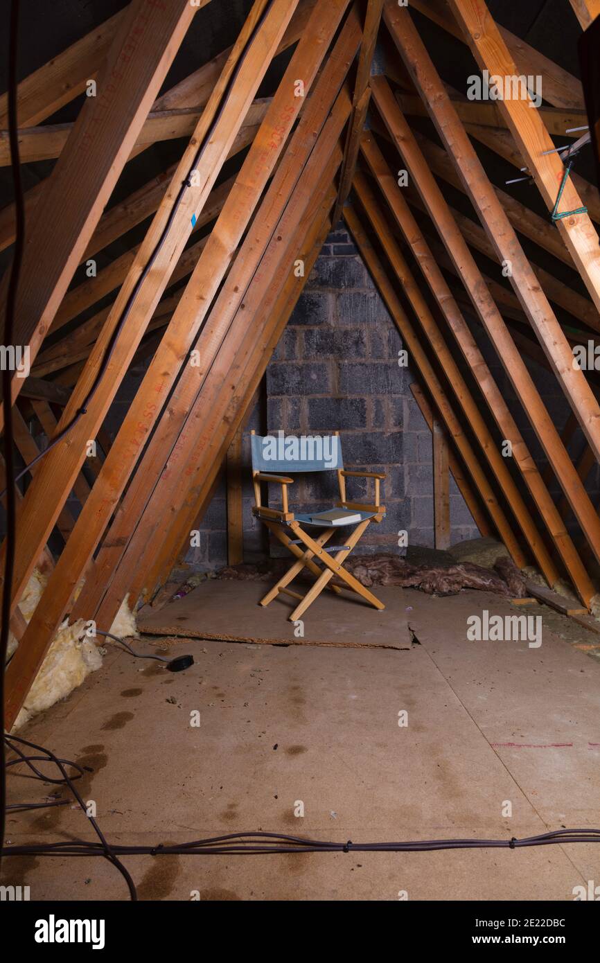 Leerer Stuhl auf dem Dachboden, mit einem Buch auf dem Sitz. Stockfoto
