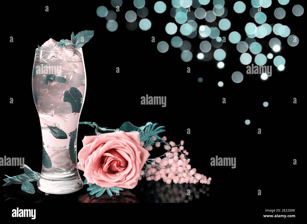 Cocktail mit Minze und Blumen, auf schwarzem Hintergrund mit Bokeh. Getöntes Bild Stockfoto