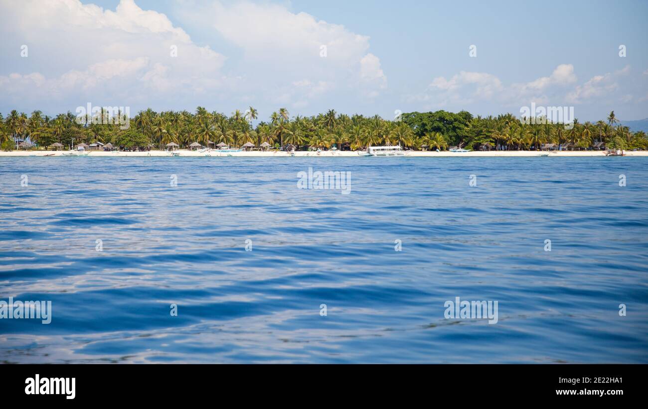 Türkisfarbene Lagune und tropische Insel. Eine Insel mit Palmen in einem Atoll im Ozean an einem Sommertag. Stockfoto