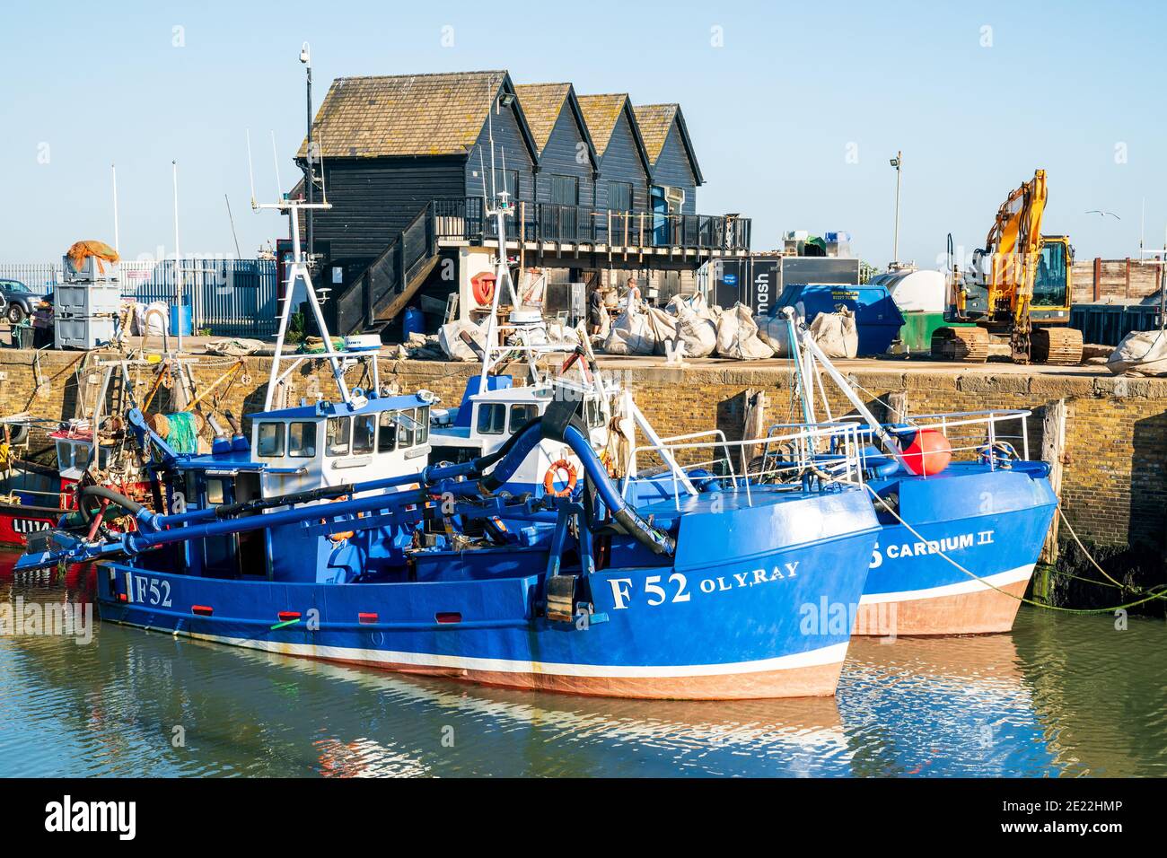 Fischerboote liegen an einem sonnigen Sommertag am Whitstable Hafen mit klarem blauen Himmel darüber. Diese Fischerboote werden für Auster- und Muschelfische verwendet. Stockfoto