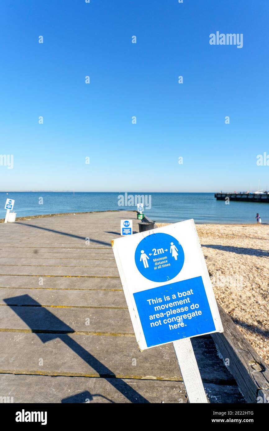 COVID soziale Distanzschilder am Meer in Witsable, Kent. Schilder sagen, es ist ein Boot Bewegung Bereich nicht versammeln, Meer und blauen Himmel Hintergrund. Stockfoto