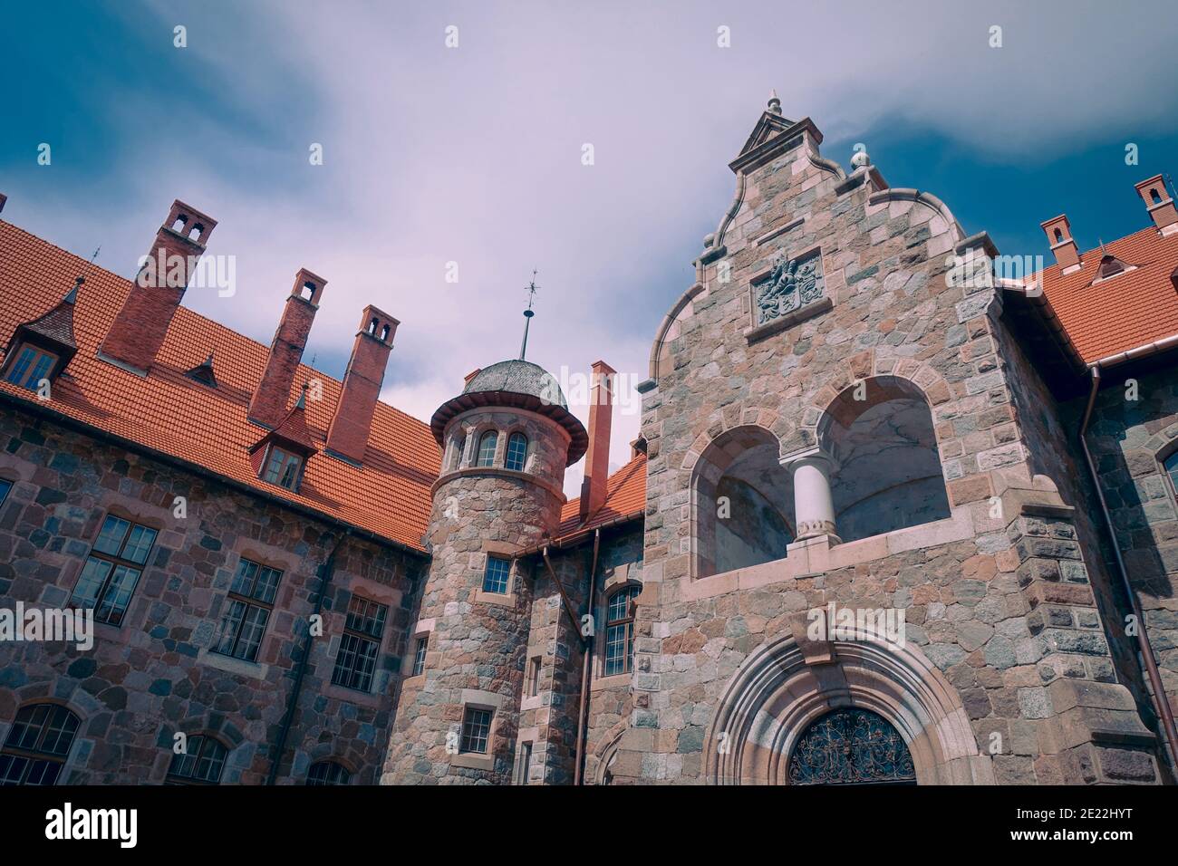 Cesvaine Palace in Lettland, im Sommer. Ansicht von unten, gegen einen blauen Himmel. Ein antikes Gebäude im gotischen Stil, mit einem orangefarbenen Dach. Stockfoto