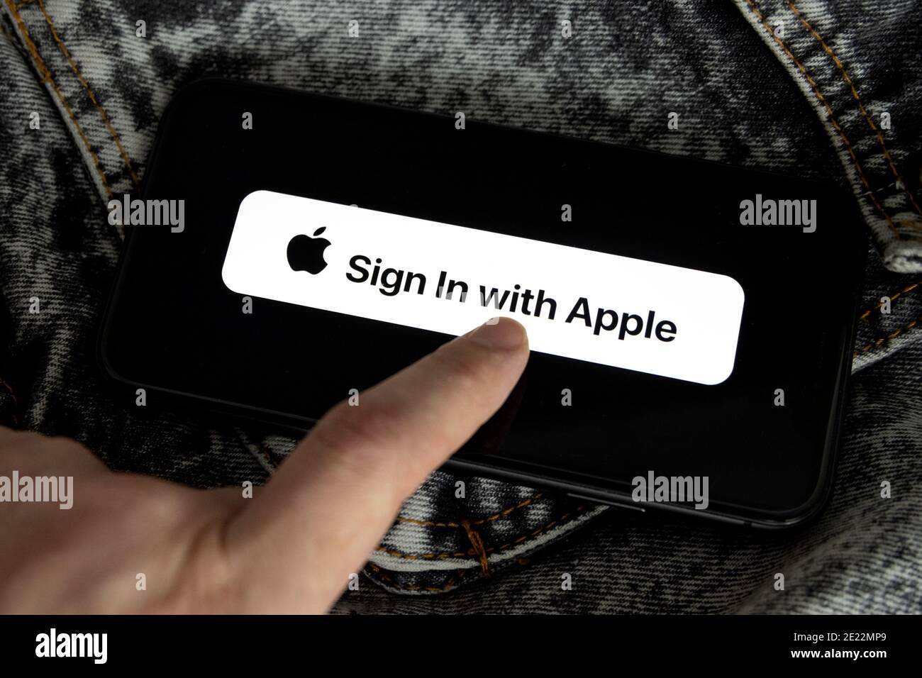 Apple ID Logo auf dem iPhone 11 Bildschirm mit schwarzem und weißem Denim Hintergrund und der Hand einer jungen Frau. Melden Sie sich mit Apple an Stockfoto