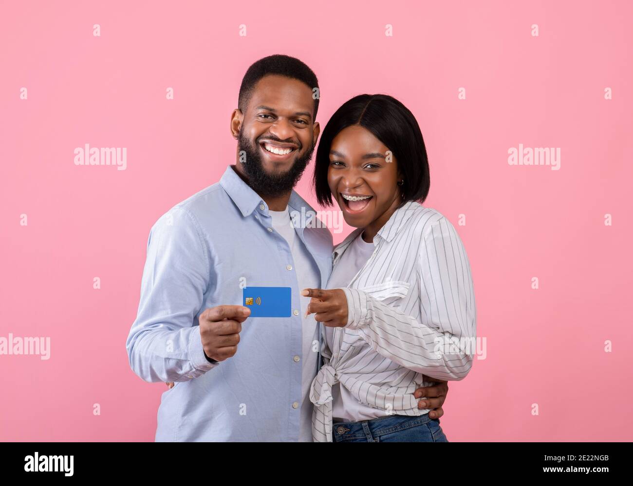Schwarzes Paar mit Kreditkarte Förderung kontaktlose Einkaufen für Valentinstag Geschenke, rosa Hintergrund Stockfoto