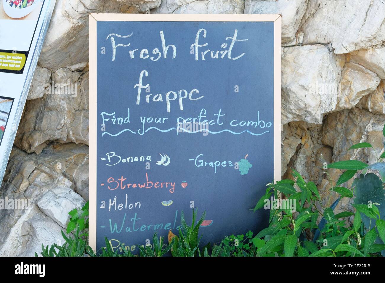 Schilder Menü schwarz Farbe mit einer Inschrift - frisches Obst Frappe. Die Tafel steht in der Nähe des Restaurants am Meeresstrand. Sonniger Tag. Stockfoto
