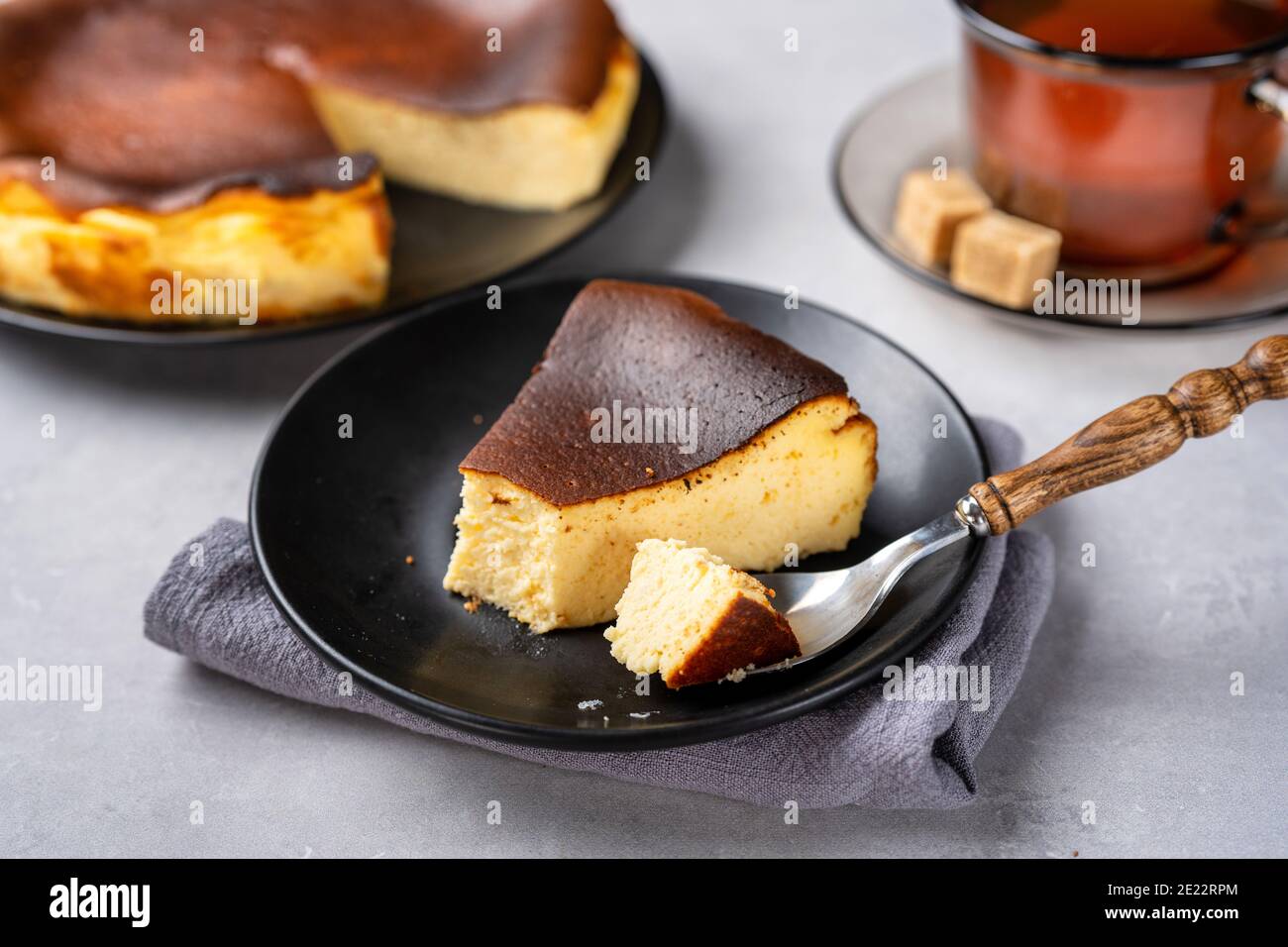 Cremiger baskischer gebrannter Käsekuchen mit einer Tasse Tee Stockfoto