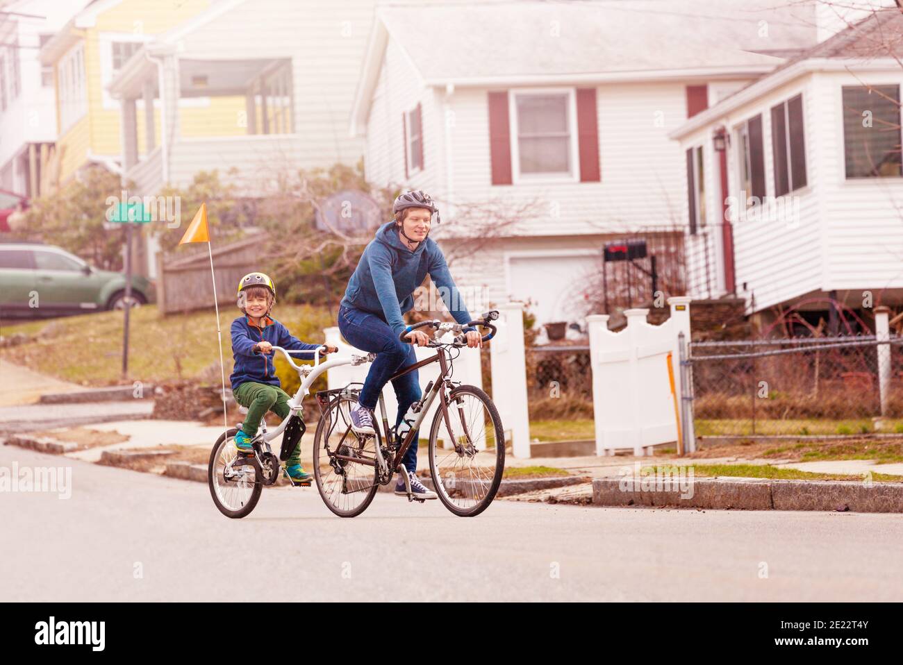 Familie Fahrrad Porträt mit kleinen glücklich Junge Fahrt auf einem Schlepptandemfahrrad, das an den Vater auf der städtischen Straßenseite angeschlossen ist Anzeigen Stockfoto