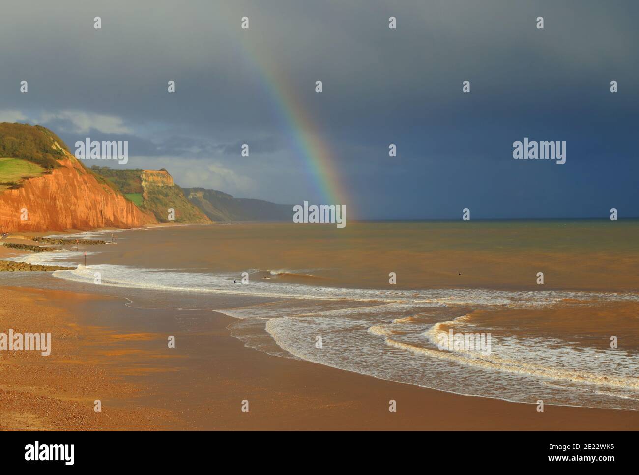 Regenbogen über Sandstrand in Sidmouth, Devon an der Jurassic Coast Stockfoto