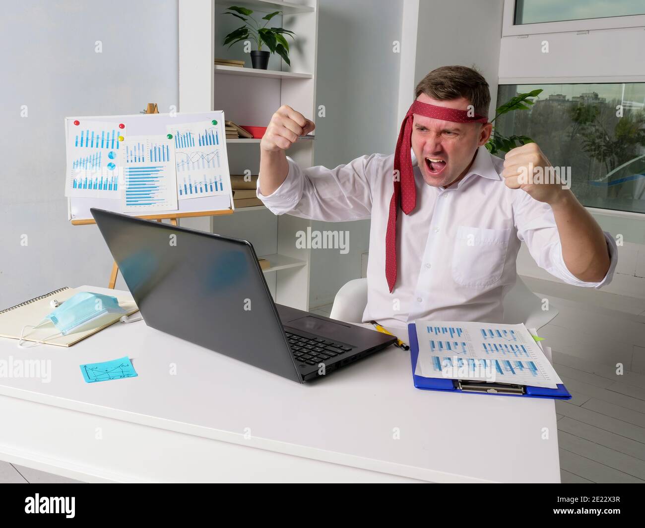Freudig müde Geschäftsmann am Bürotisch. Feier und Erfolg während der Epidemie. Stockfoto