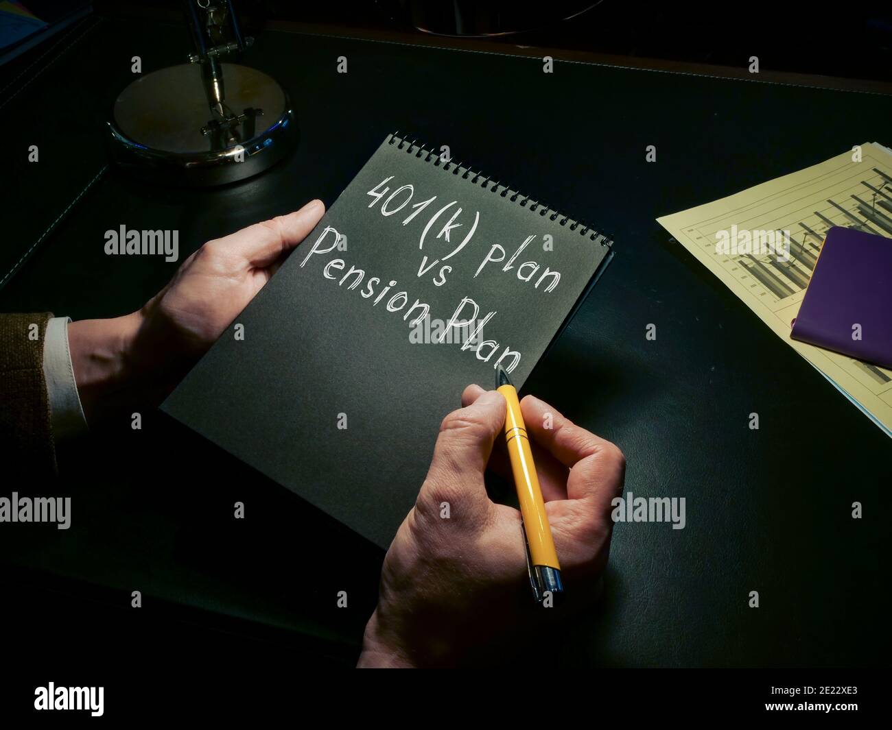 Ein Mann schreibt in einem Notebook 401k Plan vs Pensionsplan. Stockfoto Ein Mann schreibt in einem Notebook 401k Plan vs Pensionsplan. Stockfoto