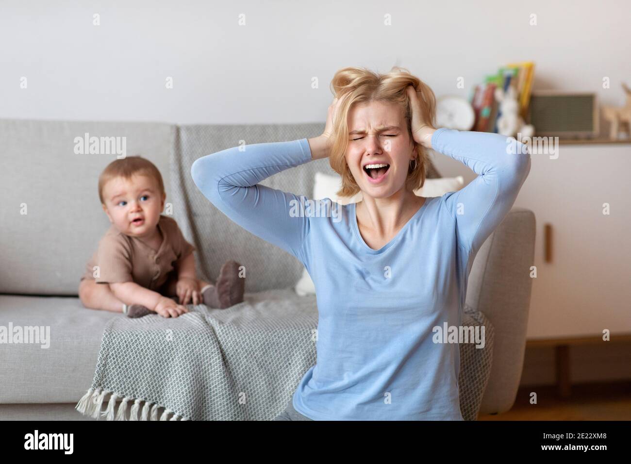 Gestresste Mutter mit Kopfschmerzen mit Baby zu Hause Stockfoto