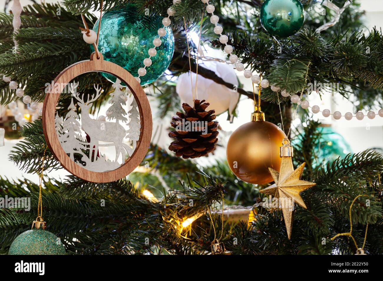 Nordische weihnachtsbaumschmuck, mit goldenen und tealfarbenen Dekorationen und weißen Perlen, die alle vom Baum hängen Stockfoto