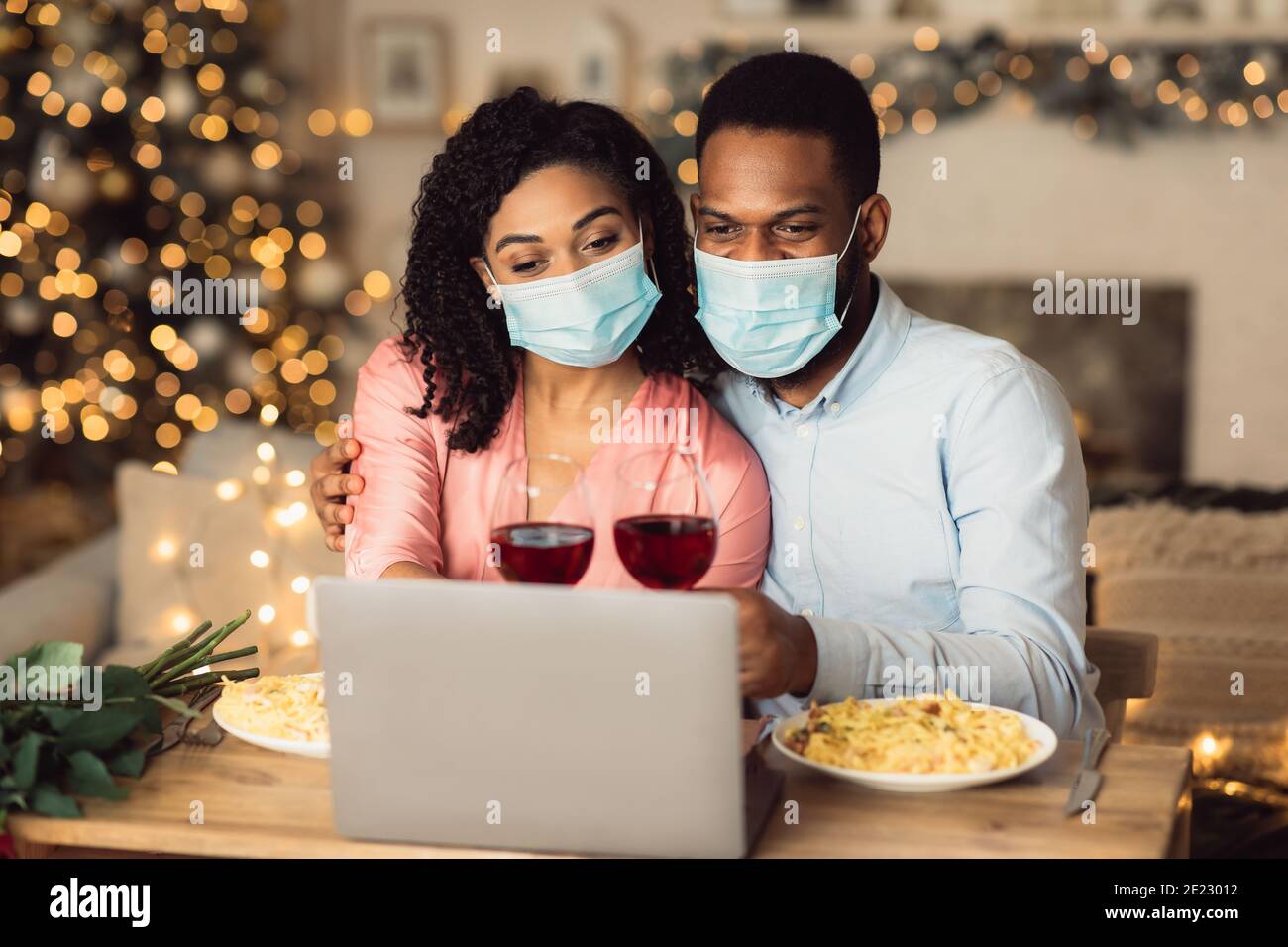 Schwarzes Paar in Masken mit Laptop, mit virtuellen Party Stockfoto