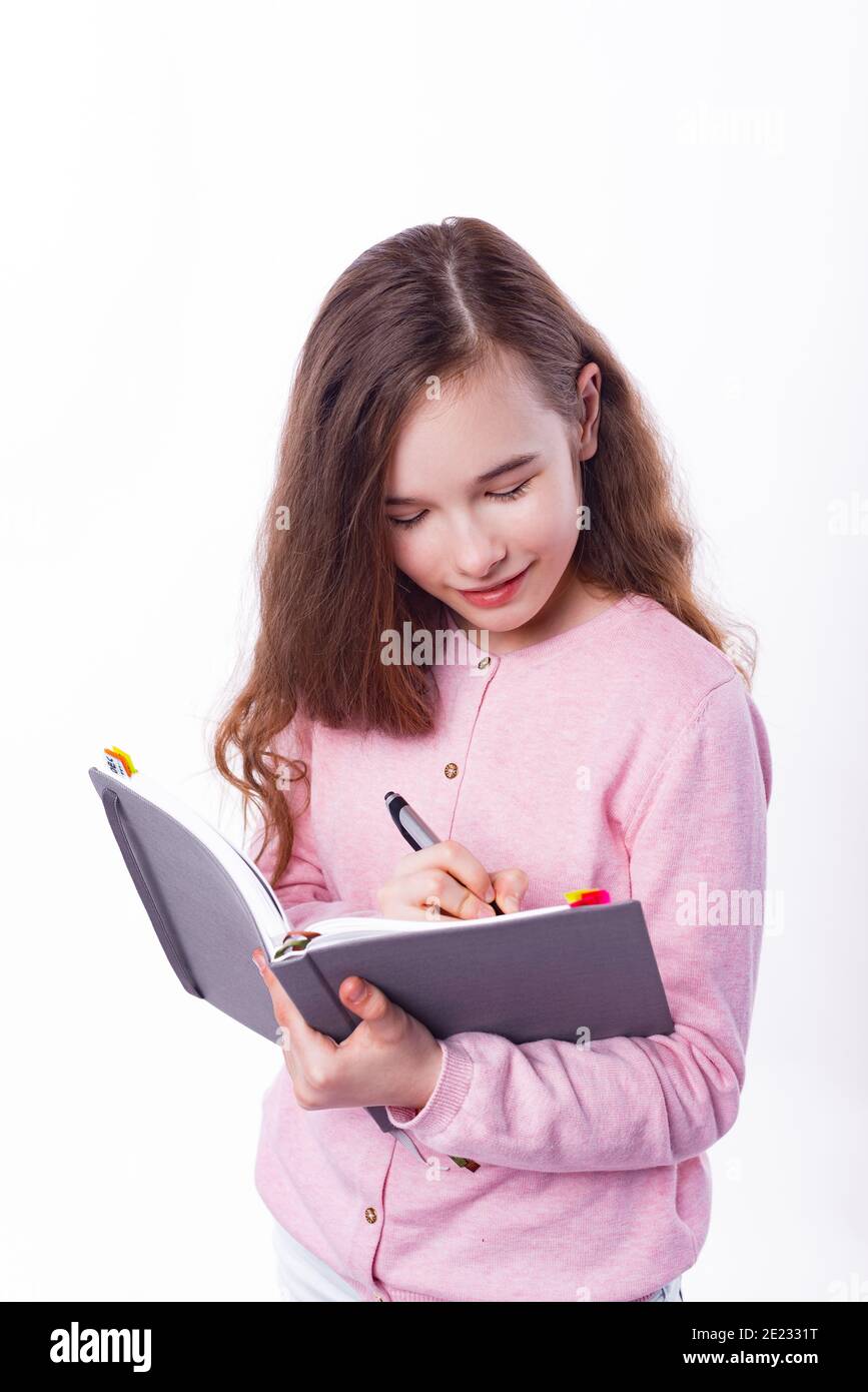Junge Schulmädchen macht Notizen in Planer über weißem Hintergrund. Stockfoto
