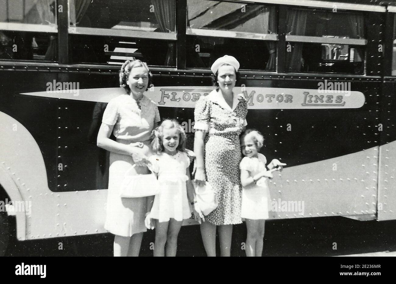 Zwei Erwachsene Damen und zwei kleine Mädchen posieren vor einem Florida Motor Lines Bus, um 1940 Stockfoto