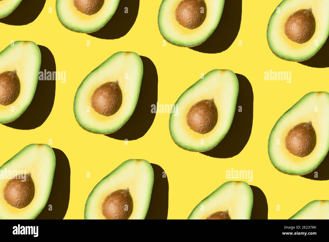 Avocado Muster auf dem gelben Hintergrund gesunde Ernährung grünes Gemüse Minimalistisch und modern Stockfoto