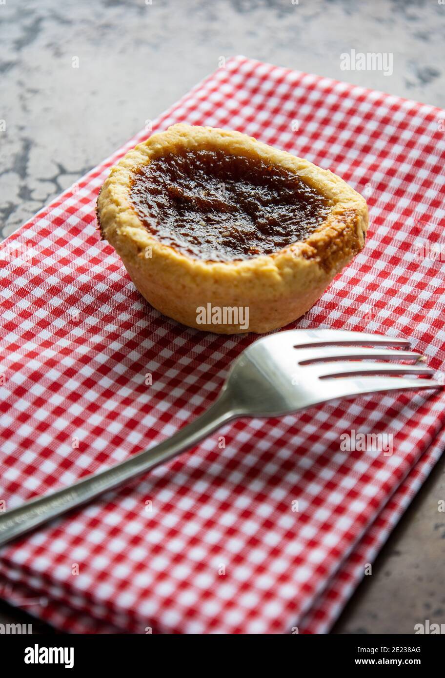 Kanadische Buttertarte EIN Spezialdessert von Kanada auf EINEM Rot und Weiß Gingham Hintergrund mit EINER Gabel Stockfoto