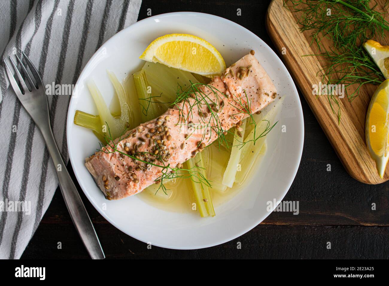 Pochierter Lachs mit Fenchel und Zitrone: Ein Stück Kräuterlachs über gekochtem Fenchel in Zitronenbrühe gekocht Stockfoto