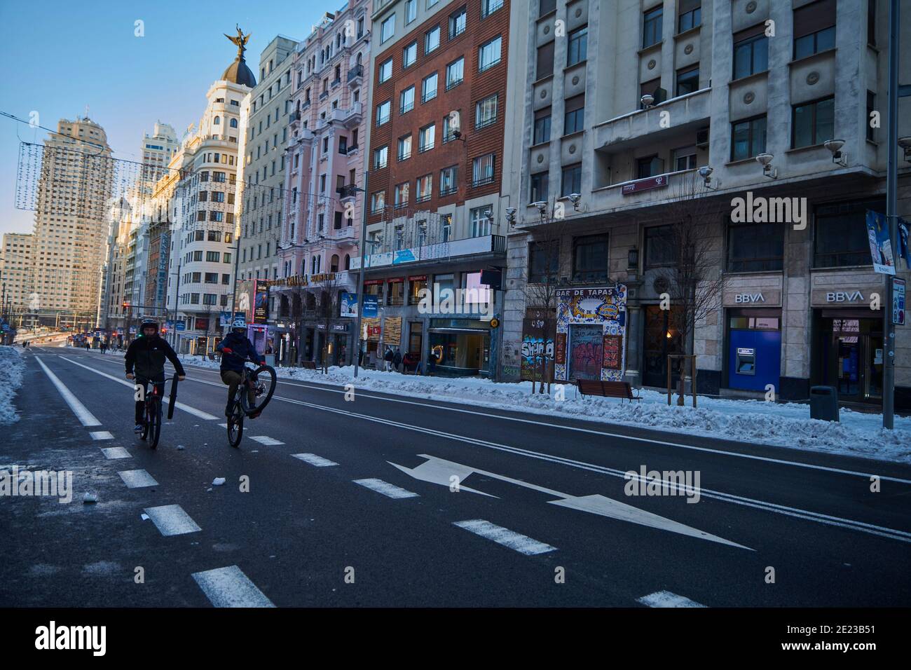 Madrid, Madrid, Spanien. Januar 2021. Tow junger Mann, der am 11. Januar 2021 in Madrid auf der verschneiten und leeren Gran Via Street radelt. Storm Filomena brachte mehr als 50 cm Schnee in die spanische Hauptstadt, der meiste seit Jahrzehnten. Kredit: Jack Abuin/ZUMA Wire/Alamy Live Nachrichten Stockfoto