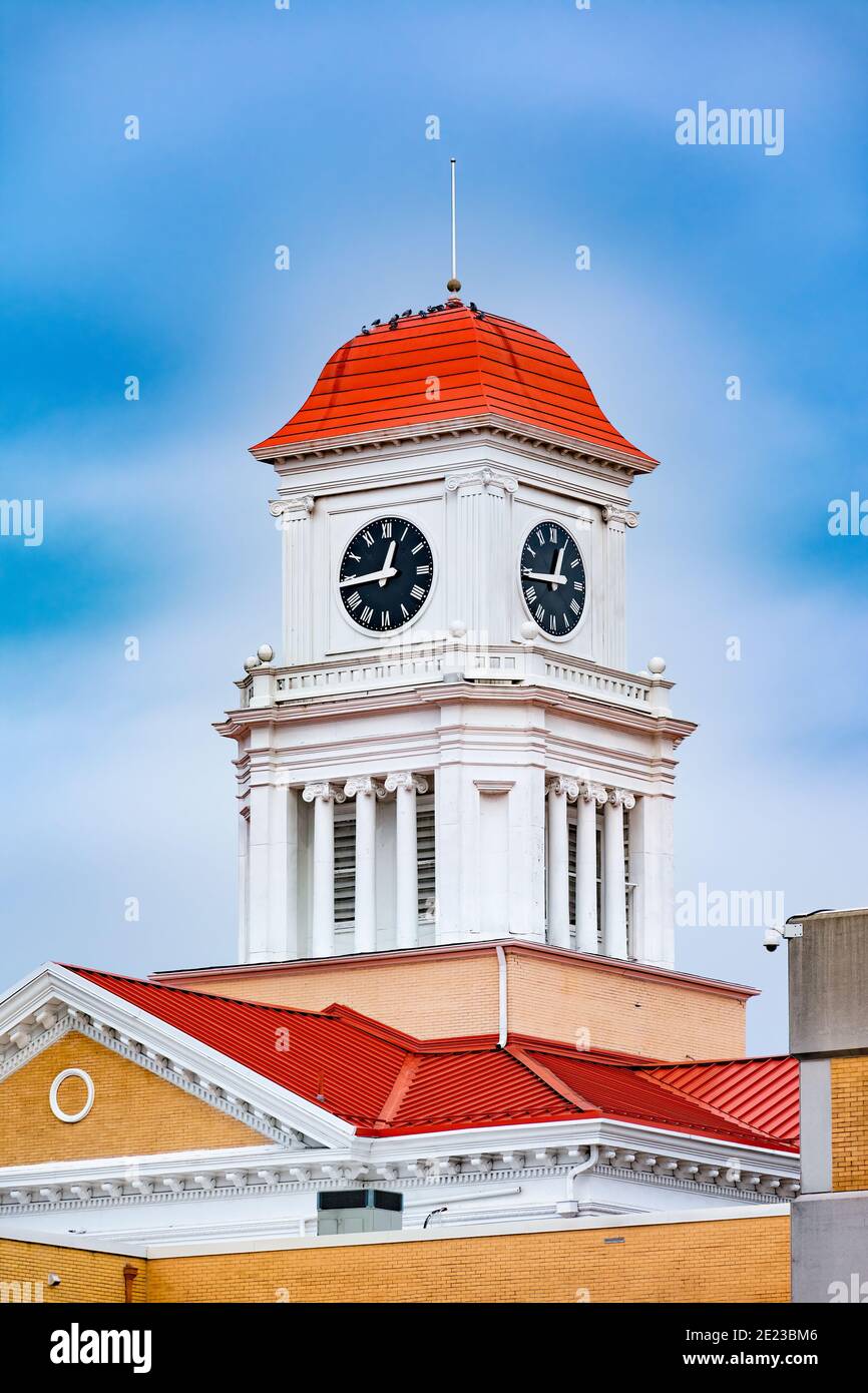 Vertikale Aufnahme eines Uhrturms auf einem kleinen Stadtgericht gegen einen blauen Himmel. Stockfoto