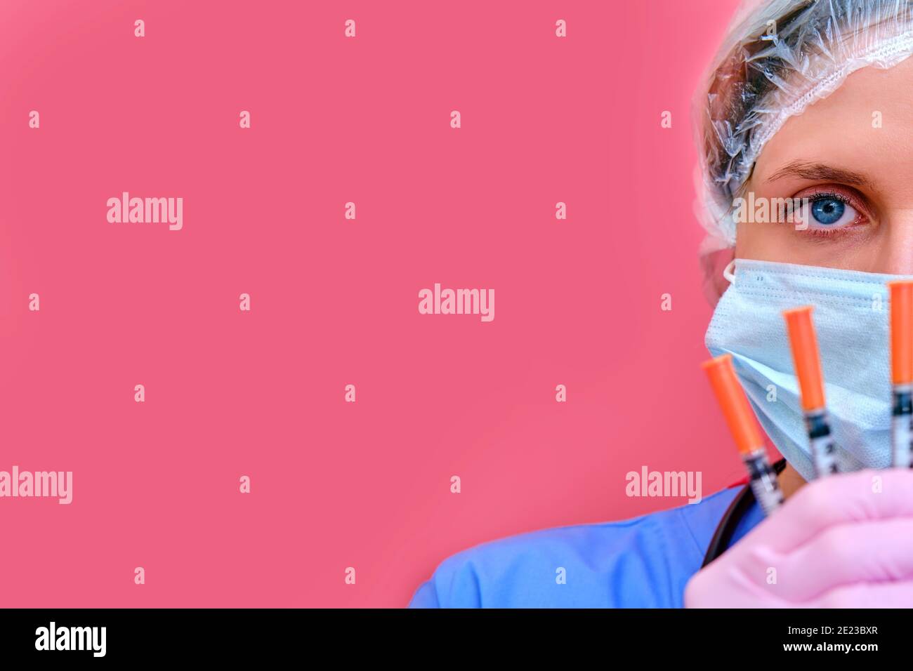 Der junge Arzt hält Spritzen in der Hand auf einem rosa Hintergrund, kopieren Platz für Text. Frau Krankenschwester mit Spritzen zur Injektion gegen Coronavirus Stockfoto