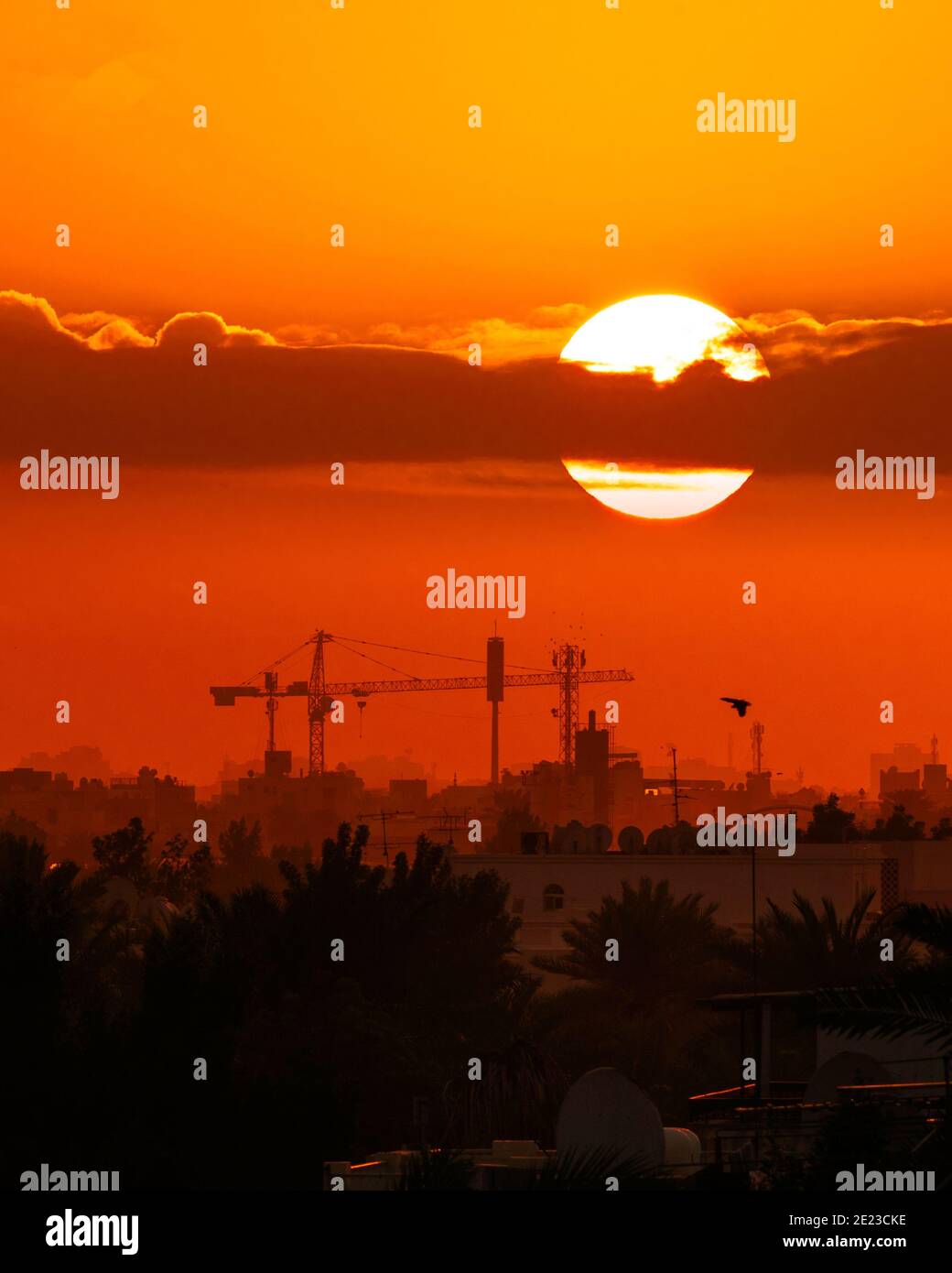 Vertikale Aufnahme des Sonnenuntergangs über der geschäftigen Stadt, in den leuchtend orangefarbenen Himmel Stockfoto