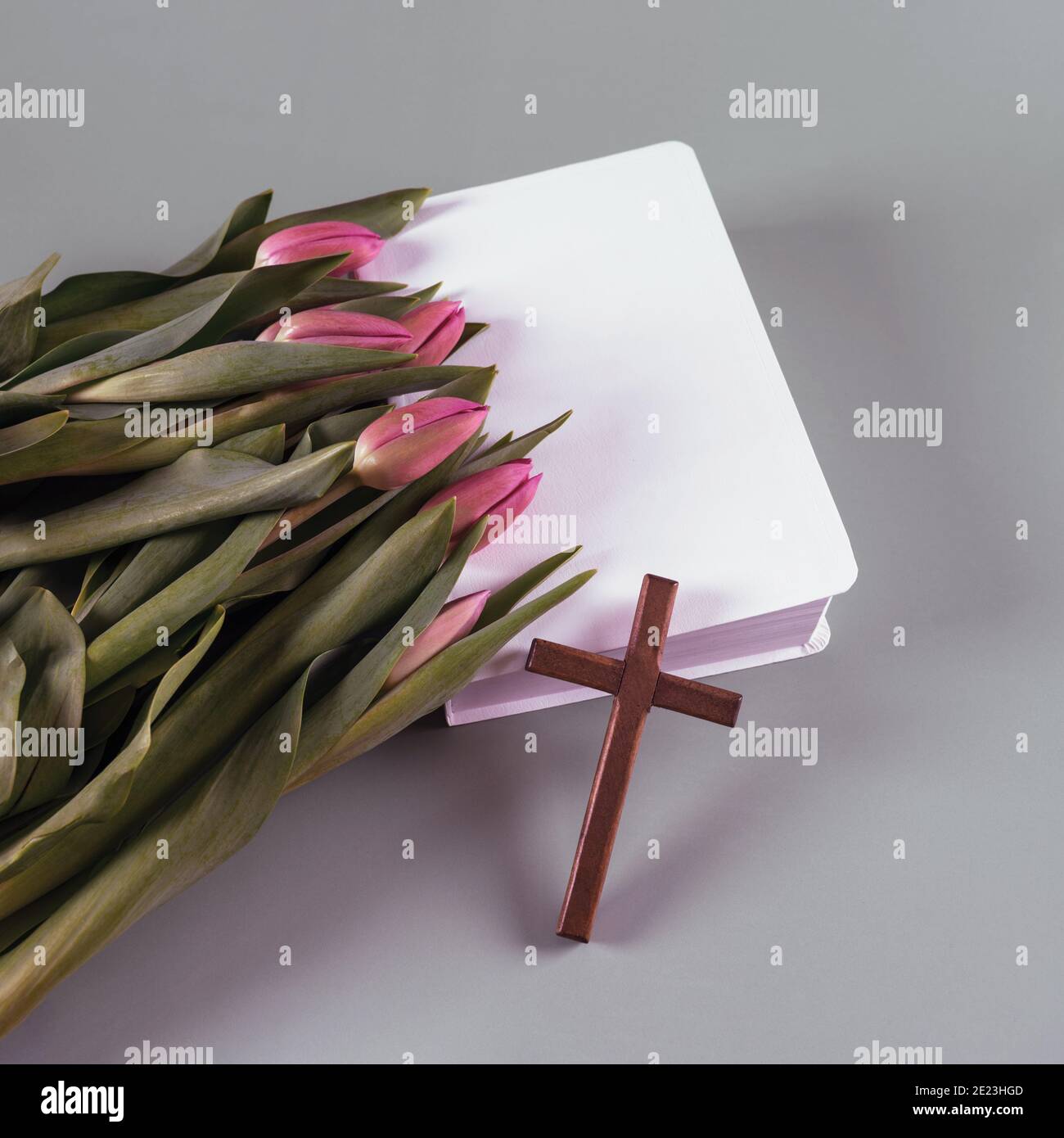 Holzkreuz, bibel und frische Frühlingsblumen. Auferstehungszeit. Kirchenkonzept.Draufsicht. Kopierraum. Stockfoto