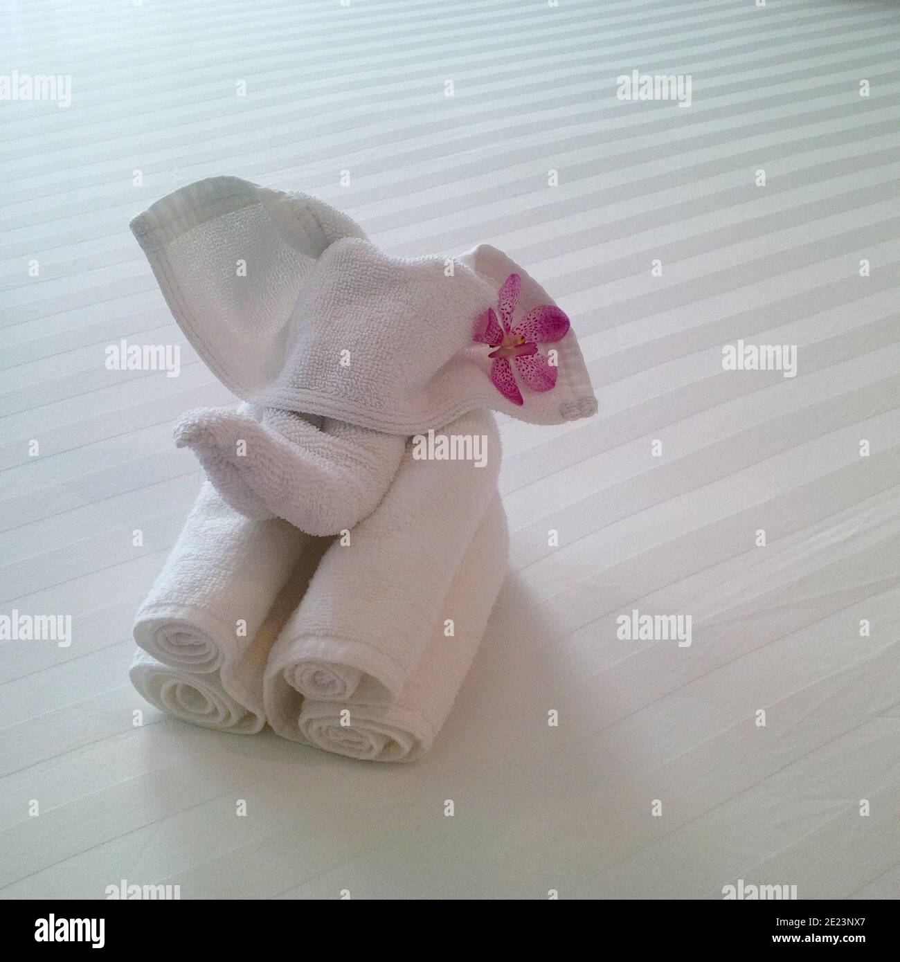 Handtuch Elefant Figur Schlafzimmer Dekor auf weißer Bettwäsche dekoriert mit Rosa Blume Stockfoto