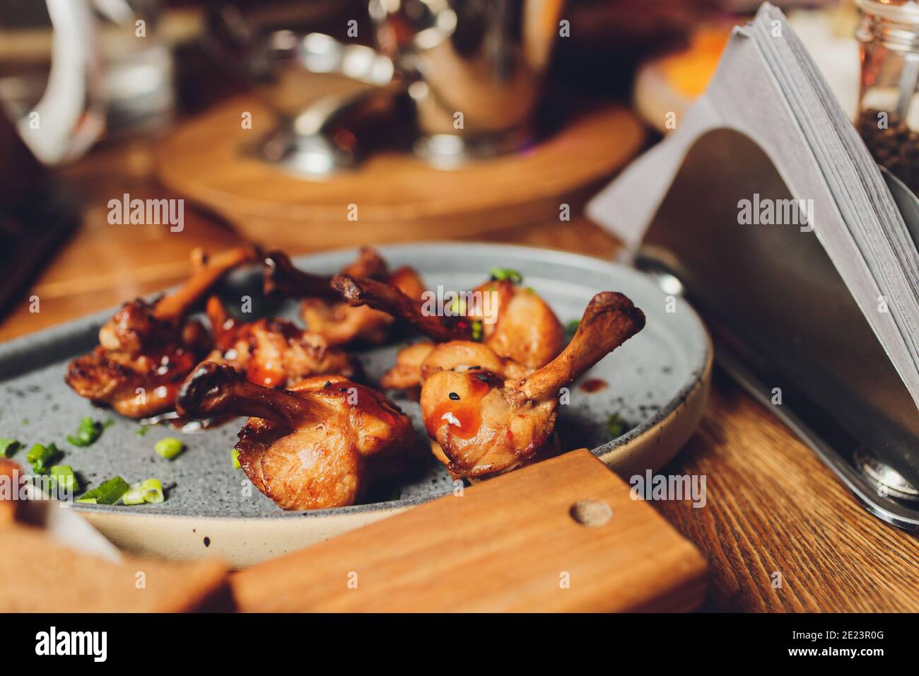 Gebratenes Huhn oder gebratene Wachtel mit Beeren und Apfelsauce und Micro Greens auf dem Teller auf schwarzem Hintergrund. Warme Fleischgerichte, Blick von oben Stockfoto