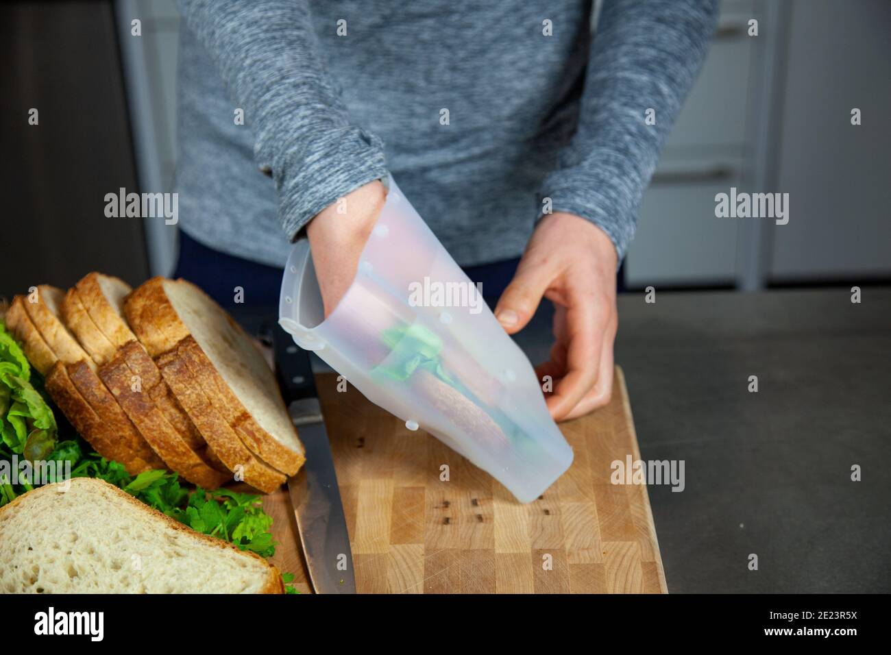 Eine Frau bereitet das Mittagessen zu und legt ein Sandwich in ein Lebensmitteltaugliches Silikonbeutel als Teil eines Zero-Waste-Lebensstils Ersetzen Sie die Kunststoffbeutel Stockfoto