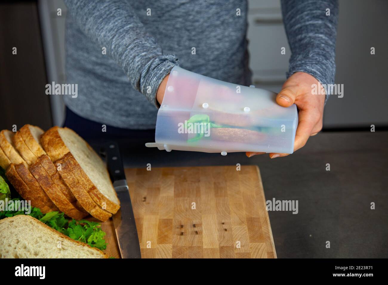 Eine Frau bereitet das Mittagessen zu und legt ein Sandwich in ein Lebensmitteltaugliches Silikonbeutel als Teil eines Zero-Waste-Lebensstils Ersetzen Sie die Kunststoffbeutel Stockfoto