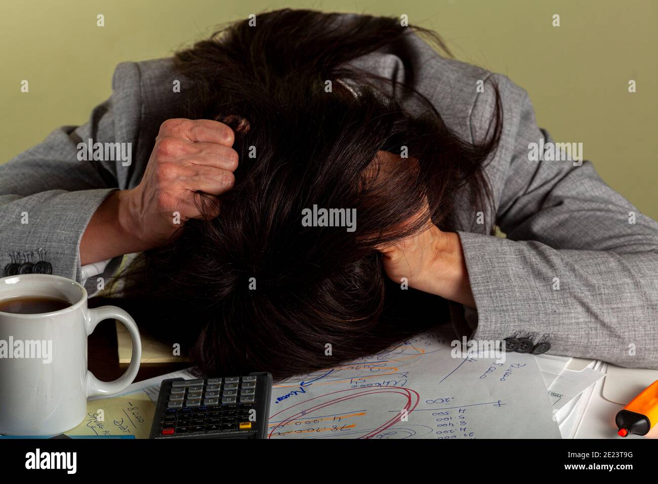 Eine gestresste kaukasische Frau zerreißt ihr Haar, während sie auf einer Bank an einem Auftrag arbeitet. Es gibt viele Notizen, Papiere und eine Kaffeetasse auf des Stockfoto