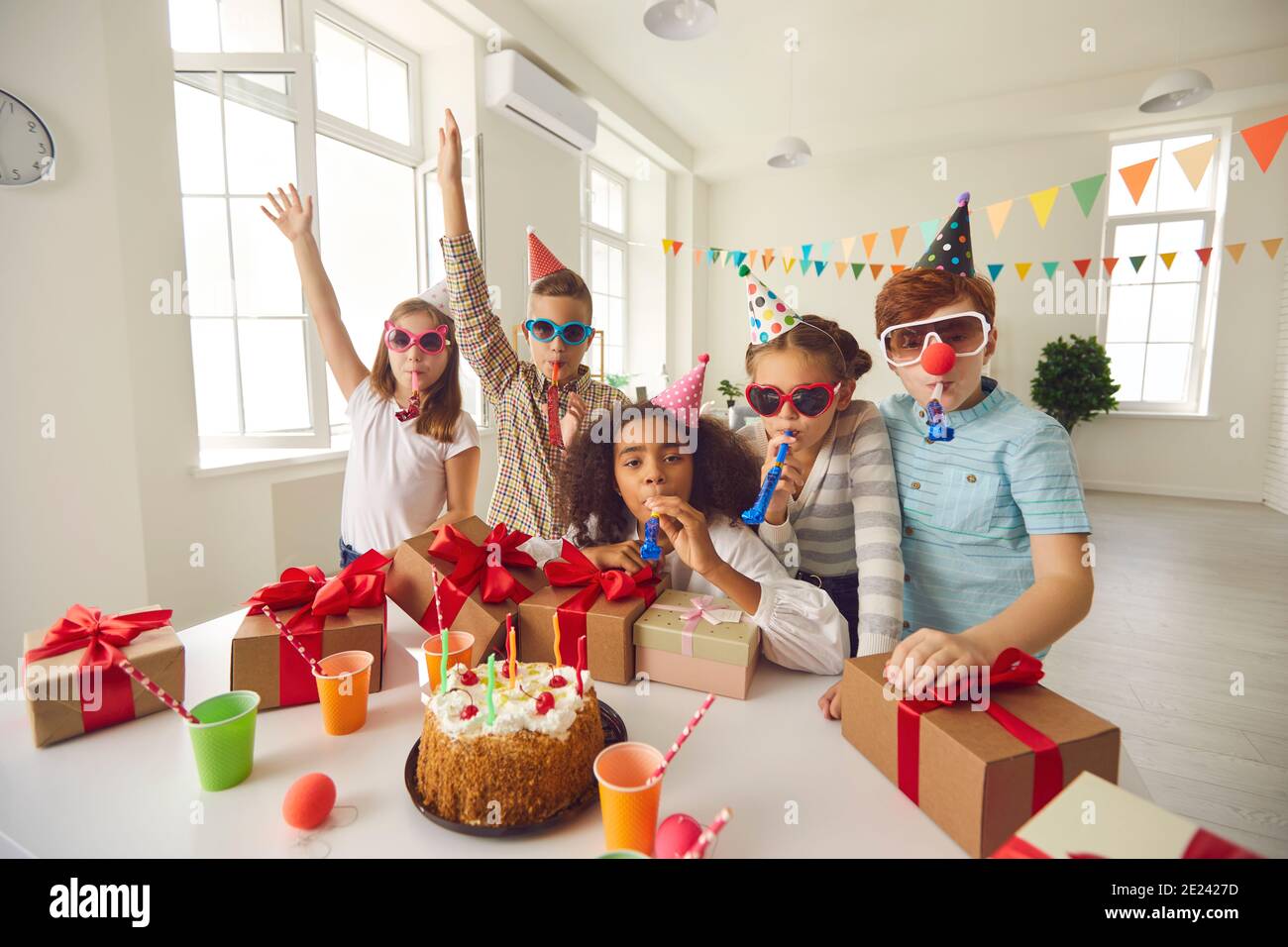 Dunkelhäutig Mädchen feiert ihren Geburtstag mit Freunden sitzen an einem Tisch, wo Geschenke und ein Kuchen. Stockfoto