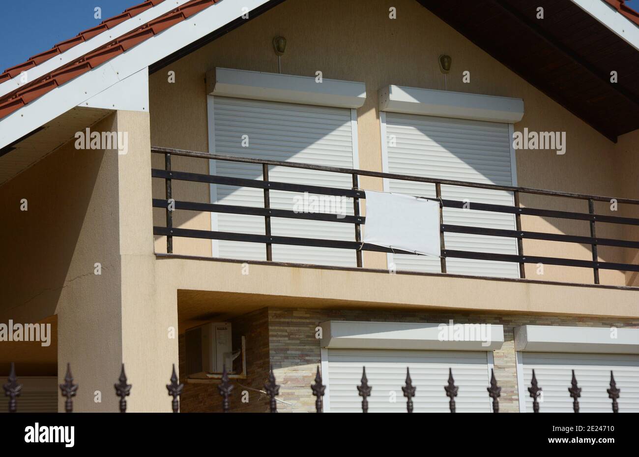 Eine Außenansicht des großen Dachgeschosses, Dachfenster geschlossen mit pvc-motorisierten Fensterrollläden, die zum offenen Balkon eines Hauses führen. Stockfoto