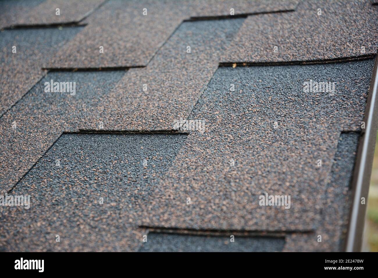 Nahaufnahme von architektonischen Asphaltschindeln auf einem Dach. Braune dimensionale Asphalt Schindeln Dach Hintergrund. Stockfoto